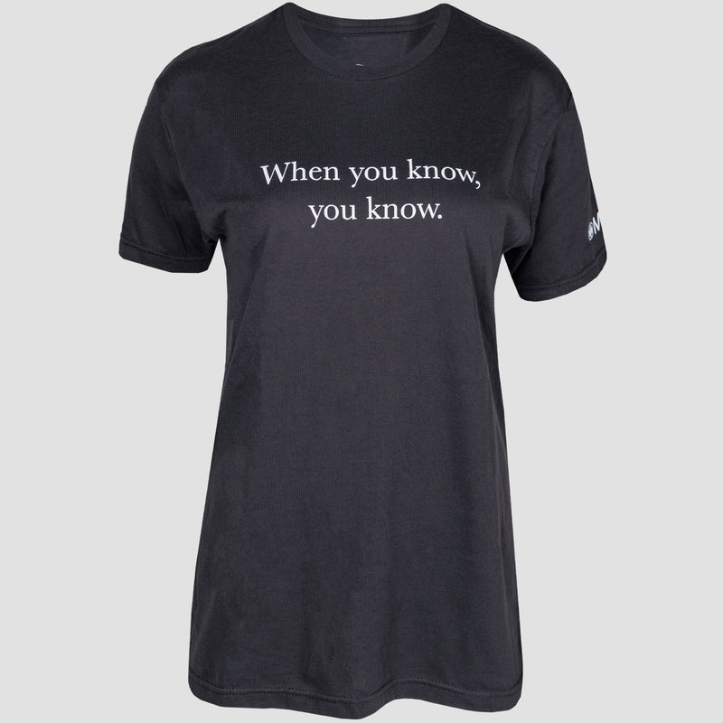 front view of black tee with "when you know, you know" printed on upper chest in white. mensa logo on left sleeve
